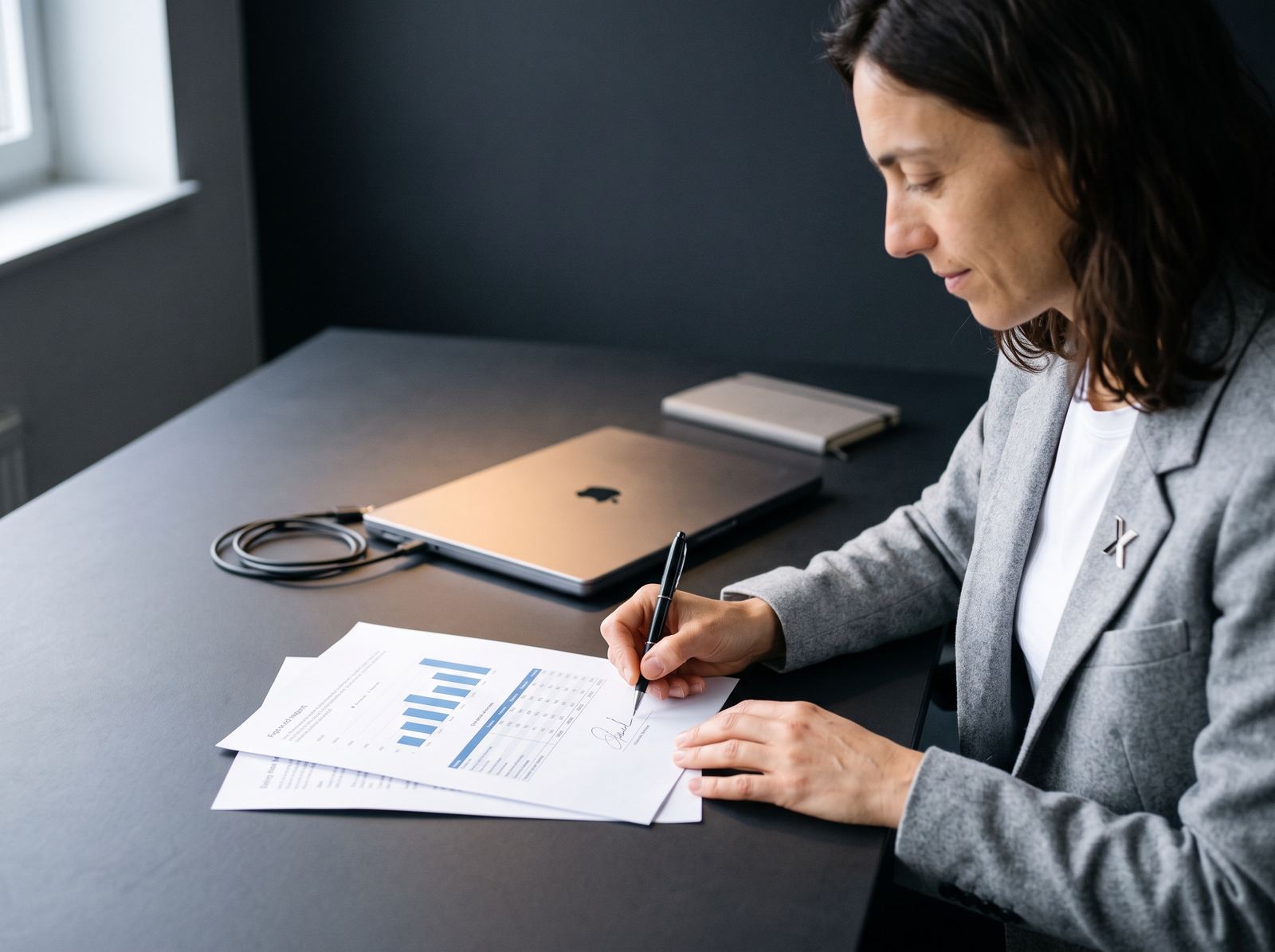 Professional signing a report with charts and data at a desk.